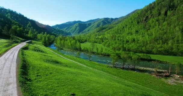 UHD 4K vue aérienne. Vol à basse altitude au-dessus d'une rivière de montagne fraîche et froide, prairie et route au matin ensoleillé d'été . — Video