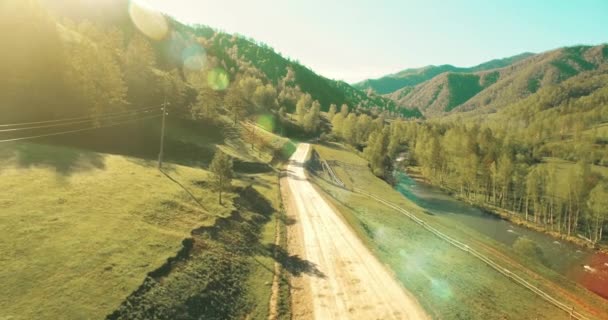 Aerial UHD 4K view. Low air flight over mountain rural dirt road and meadow at sunny summer morning. — Stock Video