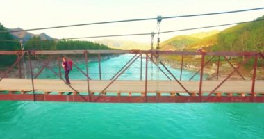 Havada uçuş genç adam turist üzerinde bir asma köprü yürümek.