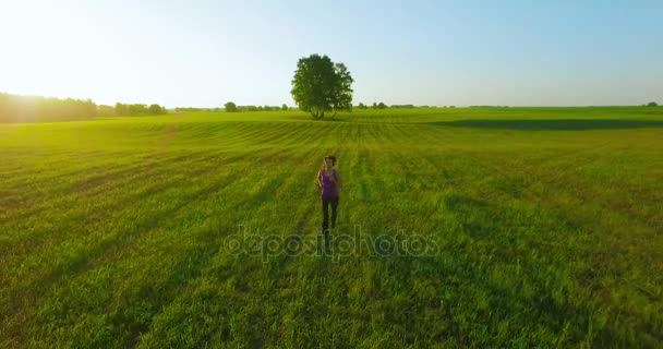 4 k Uhd 空撮。農村フィールドでスポーティな女性の前で低空飛行 — ストック動画