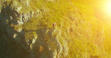 Genç yürüyüş adam uçurumun üstünde ayakta çevresinde yörünge Radyal uçuş. Uzakta görünüyor.