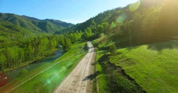 Havadan Uhd 4k görünümü. Düşük hava uçuş dağ kırsal toprak yol ve güneşli yaz sabahı, çayır üzerinde. — Stok video