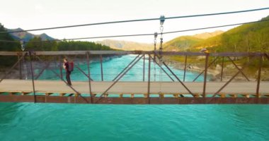 Havada uçuş genç adam turist üzerinde bir asma köprü yürümek.