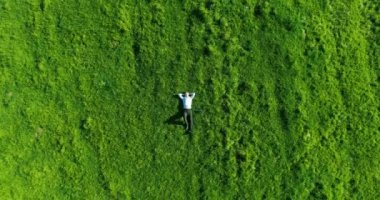 Taze yeşil çayır üzerinde yalan işadamı üzerinde dikey hareket uçuş. Üstten Görünüm üzerinde rahatlatıcı dostum.