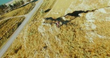 Genç yürüyüş adam uçurumun üstünde ayakta çevresinde yörünge Radyal uçuş. Uzakta görünüyor.