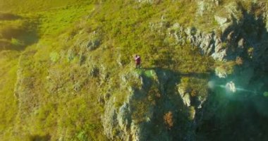 Genç yürüyüş adam uçurumun üstünde ayakta çevresinde yörünge Radyal uçuş. Uzakta görünüyor.