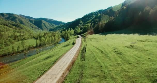 Uhd 4k Flygfoto. Låg air-flyg över berget landsbygdens grusväg och äng på solig sommarmorgon. — Stockvideo