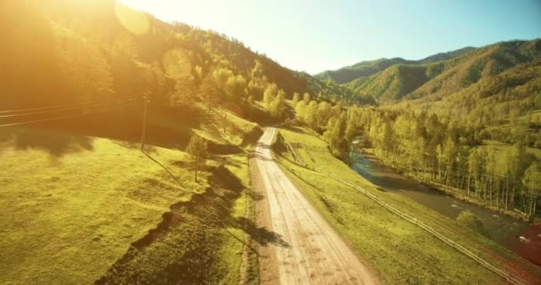 Vista aérea UHD 4K. Vuelo de aire bajo sobre carretera de tierra rural de montaña y prado en verano soleado — Vídeo de stock