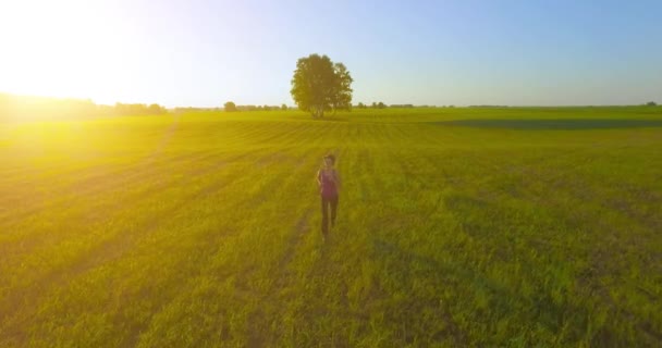 UHD 4K vista aérea. Vuelo de baja altitud frente a una mujer deportiva en el campo rural — Vídeo de stock