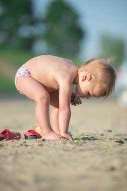 Şirin Bebek denize yakın kum plajındaki oyuncaklar ile oynama.
