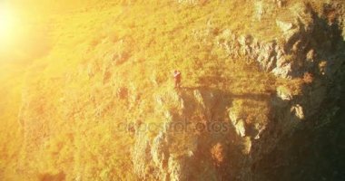 Genç yürüyüş adam uçurumun üstünde ayakta çevresinde yörünge Radyal uçuş. Uzakta görünüyor.