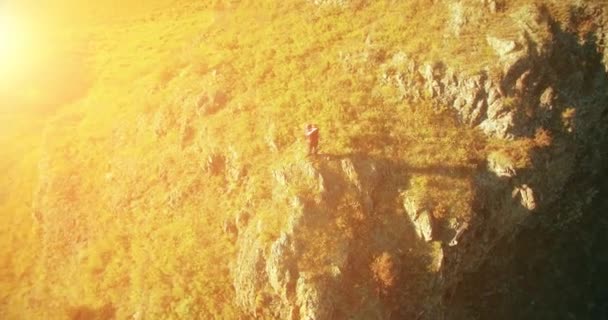 Orbitalradialflug um den jungen Wanderer herum, der oben auf der Klippe steht. Wegschauen. — Stockvideo