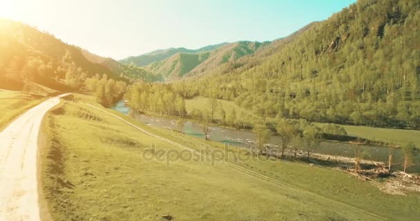 UHD 4K aerial view. Low flight over fresh cold mountain river, meadow and road at sunny summer morning. — Stock Video