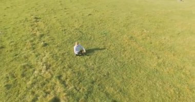 UHD 4k havadan görünümü. Defter pad ile yeşil çim sahasında oturan işadamı üzerinde düşük yörünge uçuş