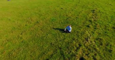 UHD 4k havadan görünümü. Defter pad ile yeşil çim sahasında oturan işadamı üzerinde düşük yörünge uçuş