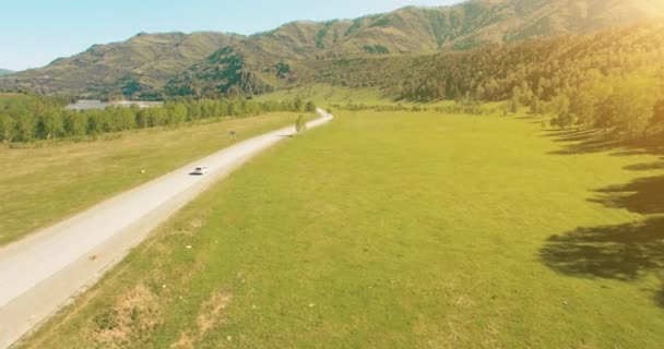Vuelo sobre los coches en un camino sinuoso en las colinas y el prado. Carretera rural abajo . — Vídeos de Stock