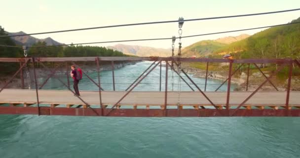 Воздушный полет над молодым человеком туристом по подвесному мосту . — стоковое видео