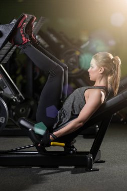 Bacaklar için ağırlıklar basın makine kullanan sportif kadın. Spor salonu.