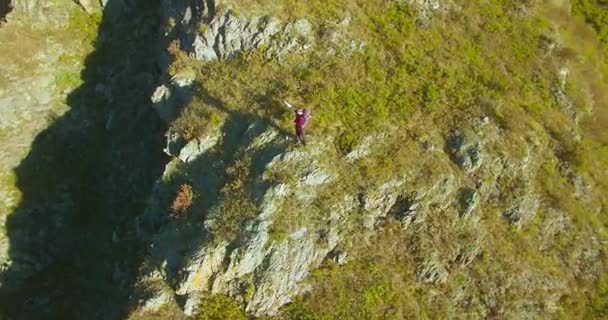 Volo radiale orbitale attorno al giovane escursionista in piedi sulla scogliera. Mani in alto, vincitore. — Video Stock