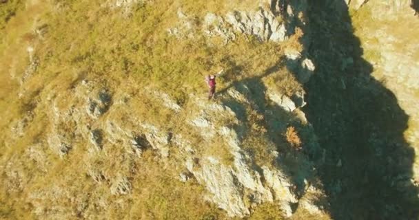 Volo radiale orbitale attorno al giovane escursionista in piedi sulla scogliera. Mani in alto, vincitore. — Video Stock