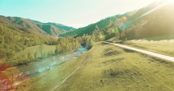 UHD 4k luchtfoto. Lage vlucht over verse koude berg rivier, weide en weg bij zonnige Zomerochtend. — Stockvideo