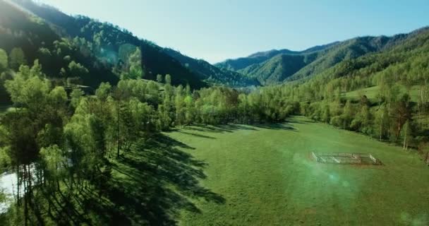 UHD 4K vista aérea. Vuelo bajo sobre el río fresco y frío de la montaña, prado y carretera en la soleada mañana de verano . — Vídeos de Stock
