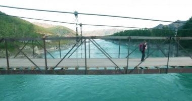 Havada uçuş genç adam turist üzerinde bir asma köprü yürümek.