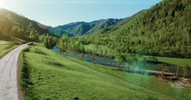 UHD 4k havadan görünümü. Düşük uçuş taze soğuk dağ nehir, çayır ve yola güneşli yaz sabahı. — Stok video