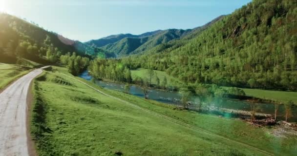 UHD 4k luchtfoto. Lage vlucht over verse koude berg rivier, weide en weg bij zonnige Zomerochtend. — Stockvideo