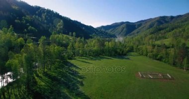 Güneşli yaz sabahında taze dağ nehri ve çayır üzerinde uçuşun ortasında. Aşağıdaki kırsal toprak yol.