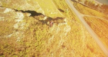 Genç yürüyüş adam uçurumun üstünde ayakta çevresinde yörünge Radyal uçuş. Uzakta görünüyor.