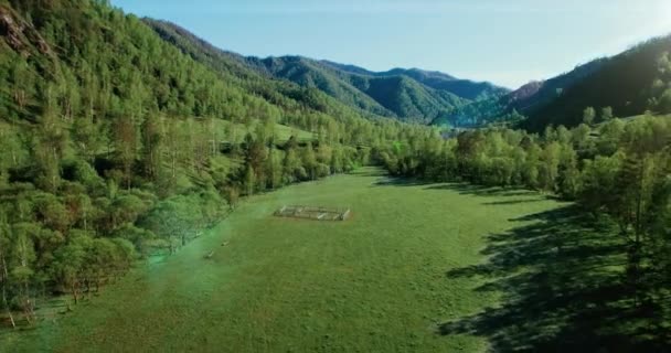 Vista aerea UHD 4K. Basso volo sul fresco fiume di montagna freddo, prato e strada al sole mattina d'estate . — Video Stock