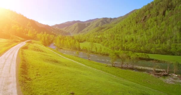 UHD 4K aerial view. Low flight over fresh cold mountain river, meadow and road at sunny summer morning. — Stock Video