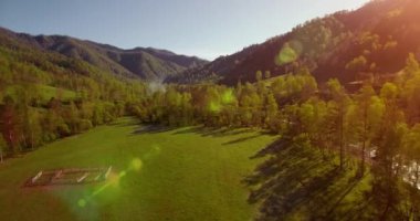 Güneşli yaz sabahında taze dağ nehri ve çayır üzerinde uçuşun ortasında. Aşağıdaki kırsal toprak yol.