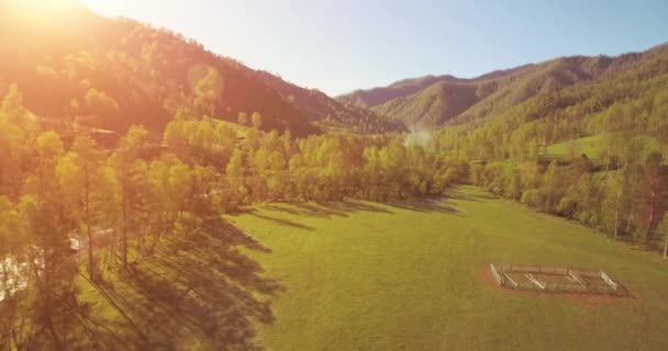 Mid air flyvning over frisk bjerg flod og eng på solrig sommer morgen. Landdistrikterne grusvej nedenfor. – Stock-video