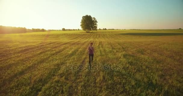 UHD 4K aerial view. Low altitude flight in front of sporty woman at rural field — Stock Video