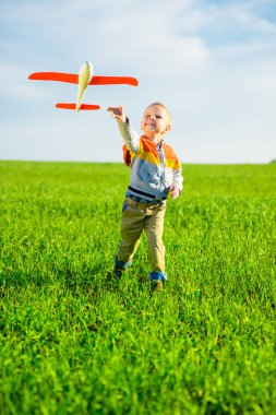 Oyuncak uçak mavi yaz gökyüzü ve yeşil alan arka plan karşı oynamaktan mutlu çocuk.