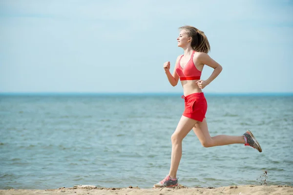 Young lady running at the sunny summer sand beach. Workout.  Jog