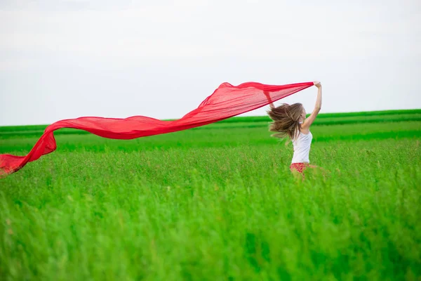 Jonge dame runing met weefsel in groene veld. Vrouw met sjaal. — Stockfoto