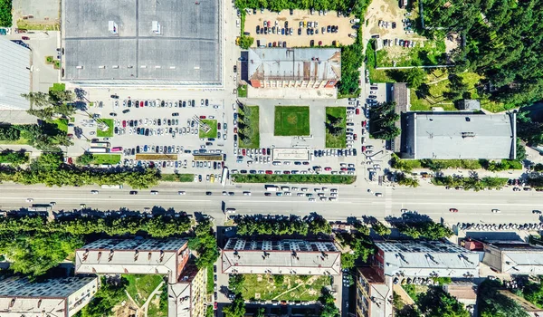 Vista aérea de la ciudad con encrucijadas y caminos, casas, edificios, parques y estacionamientos. Imagen panorámica soleada de verano —  Fotos de Stock