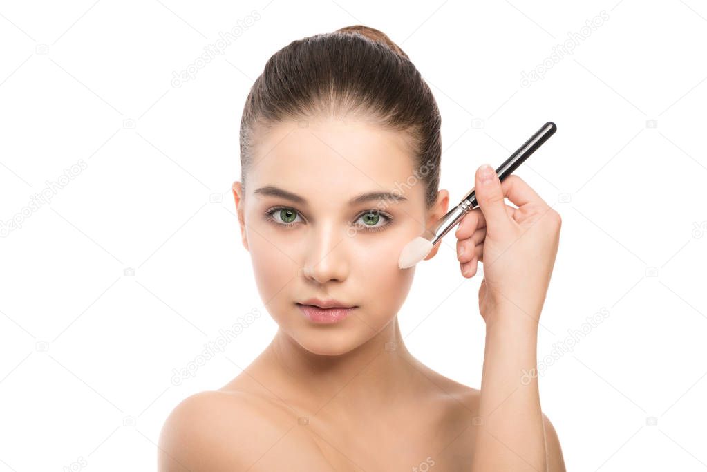 Young brunette woman with clean face. Girl perfect skin applying cosmetic brush. Isolated on a white.