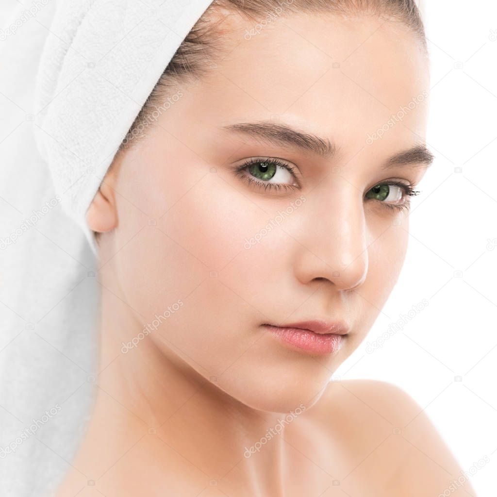 Beautiful young brunette woman with clean face and towel on her head. Isolated.