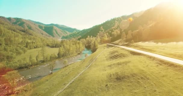 UHD 4k luchtfoto. Lage vlucht over verse koude berg rivier, weide en weg bij zonnige Zomerochtend. — Stockvideo