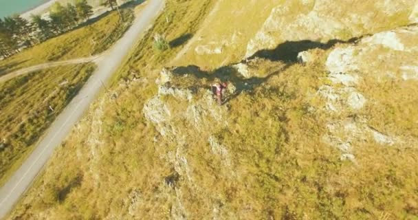 Orbitalradialflug um den jungen Wanderer herum, der oben auf der Klippe steht. Wegschauen. — Stockvideo