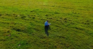 UHD 4k havadan görünümü. Defter pad ile yeşil çim sahasında oturan işadamı üzerinde düşük yörünge uçuş