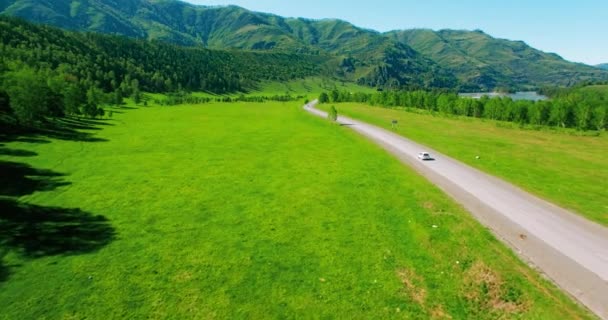 Lot nad samochodami po krętej drodze w wzgórz i łąka. Obszarów wiejskich autostrady poniżej. — Wideo stockowe
