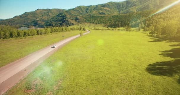 Vuelo sobre los coches en un camino sinuoso en las colinas y el prado. Carretera rural abajo . — Vídeos de Stock