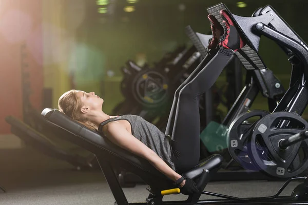 Mujer deportiva usando máquina de prensa de pesas para las piernas. Gimnasio . — Foto de Stock