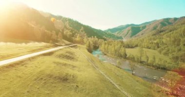 UHD 4k havadan görünümü. Düşük uçuş taze soğuk dağ nehir, çayır ve yola güneşli yaz sabahı.