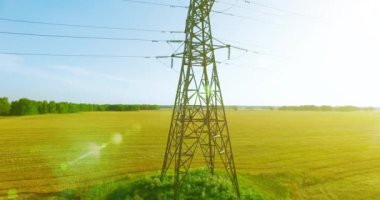 Yüksek voltajlı elektrik kulesi ve yeşil ve sarı alandaki elektrik hatları yakınında dikey hareket.